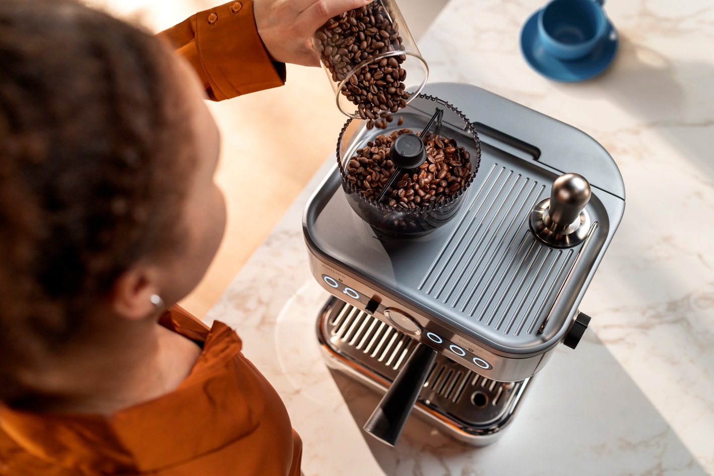 Eine junge Frau gibt Kaffeebohnen in den Kaffeebohnenbehälter der Philips Barista Brew
